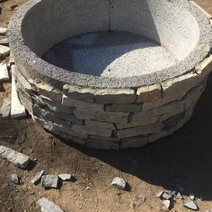 A dry-stacked stone fire pit in a backyard setting