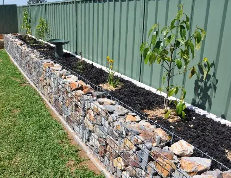 A low gabion wall along a garden border filled with stones