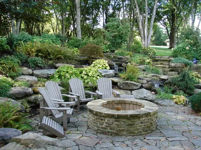 A rustic fire pit seating area with wooden benches and tree stump seating