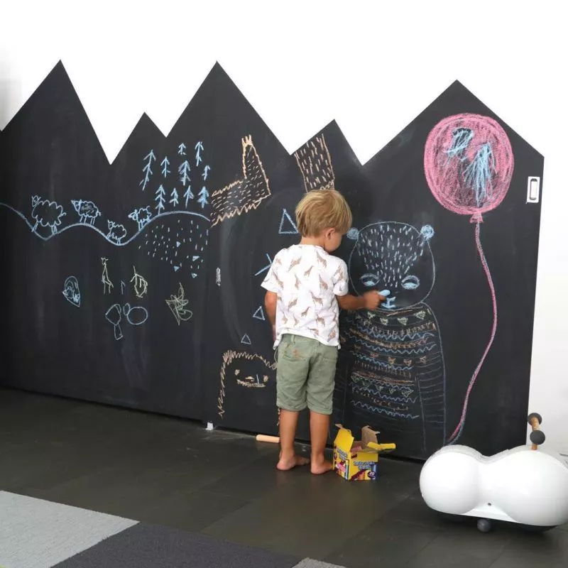 Wall in a toddler boy's room painted with chalkboard paint to encourage creativity.