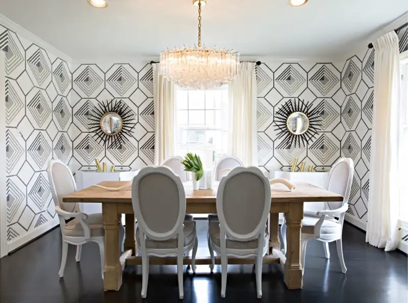 A chic dining room featuring an accent wall with geometric wallpaper.