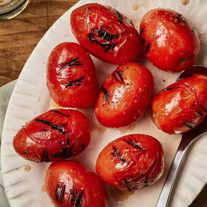 Freshly roasted tomatoes with charred skin, just off the grill, giving off a delicious smoky aroma.