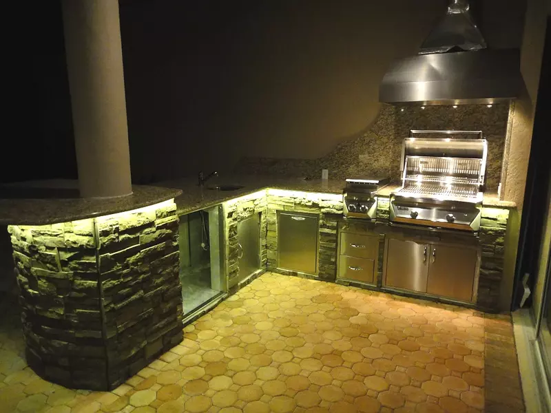 Outdoor kitchen illuminated with ambient string lights and LED strips under counters