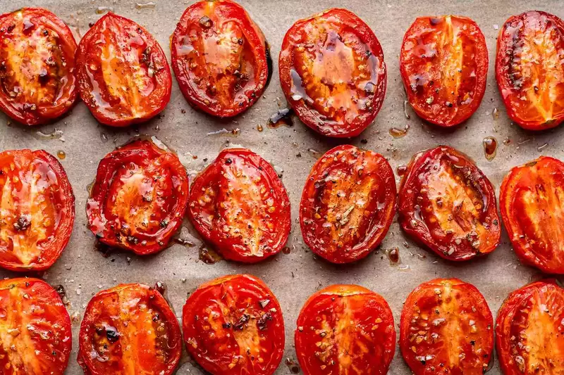 Fresh tomatoes being prepped for roasting, halved and brushed with olive oil.