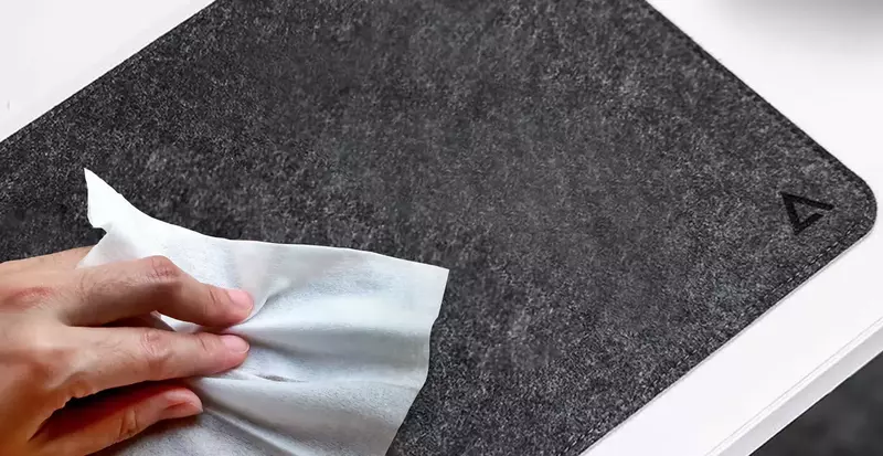 Rubber desk mat being cleaned with a soft cloth