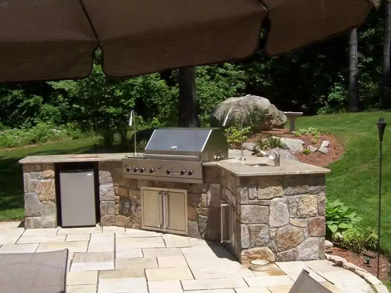 Traditional stone outdoor kitchen with wrought iron accessories and cobblestone
