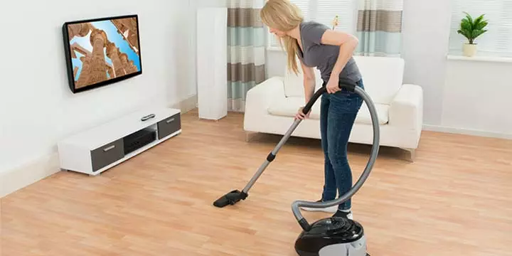 Person vacuuming a hardwood floor with a hardwood floor attachment.